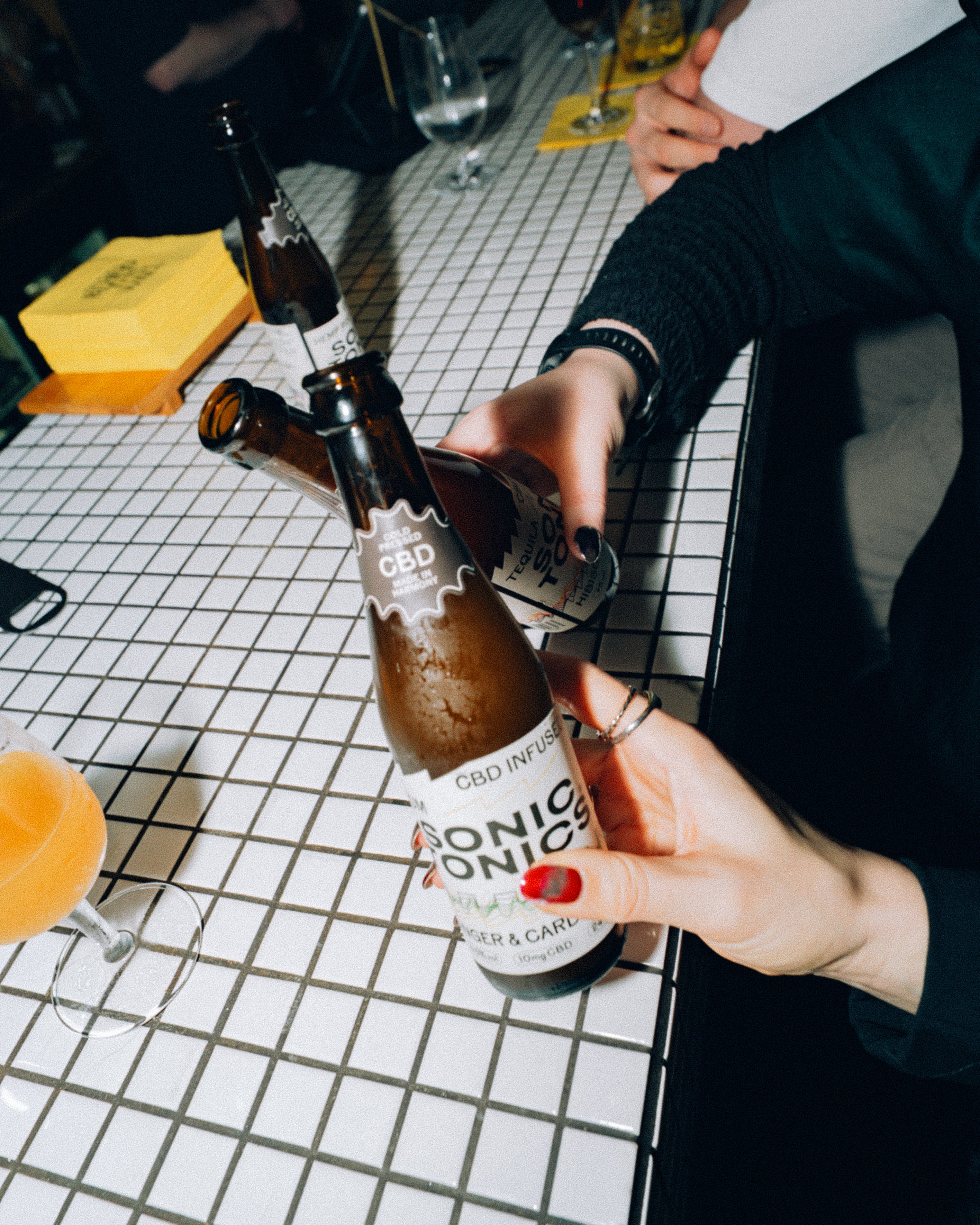 Person opening a bottle of Sonic Tonics on a tiled bar